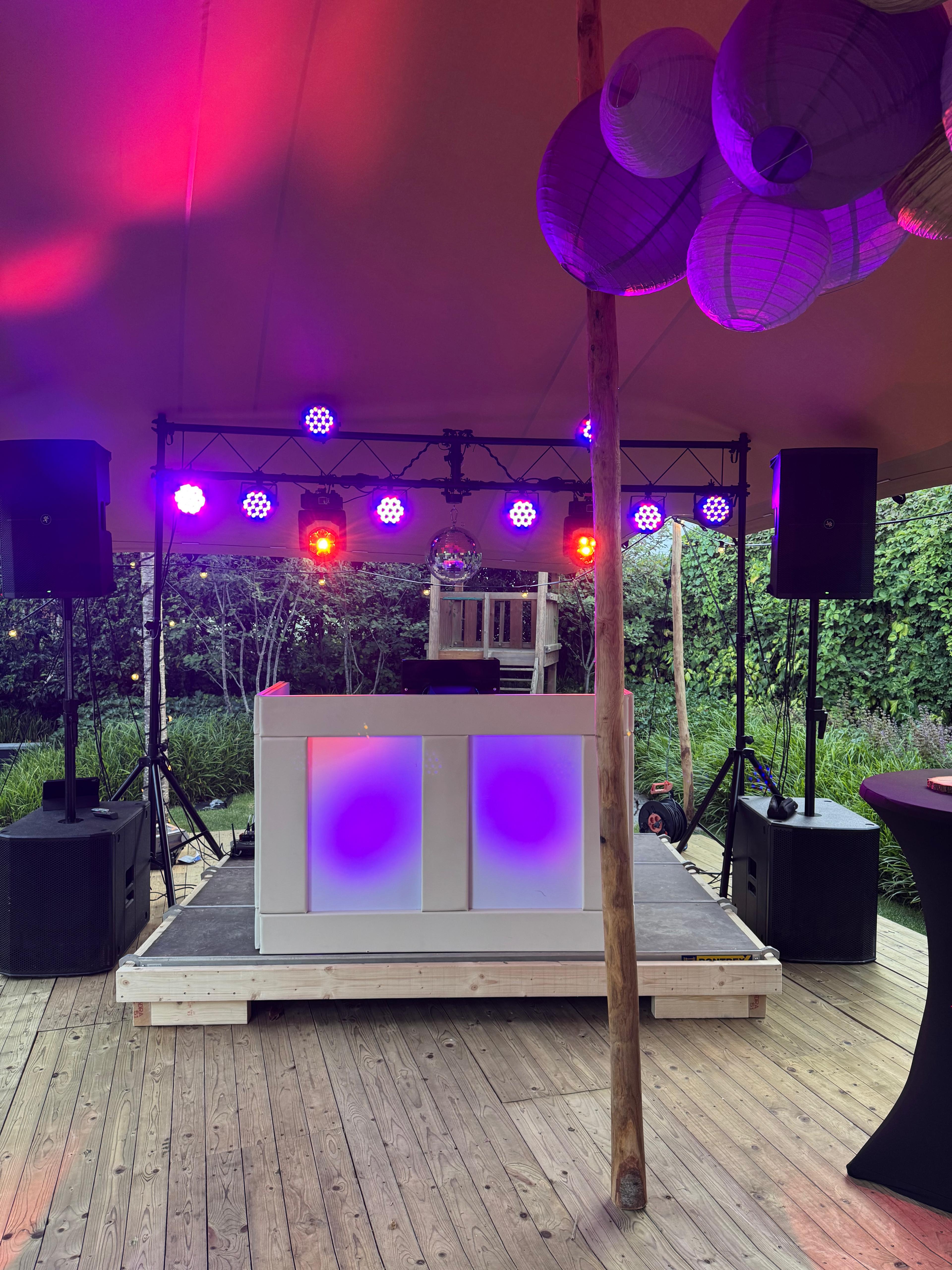 DJ booth met lichtshow en speakers op tuinfeest